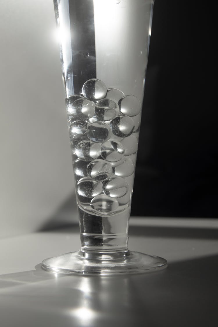 Glass Of Water With Decorative Balls Placed On Counter