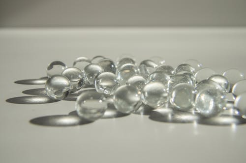 Free Closeup of heap of small transparent crystal decorative balls scattered on white table in daylight Stock Photo