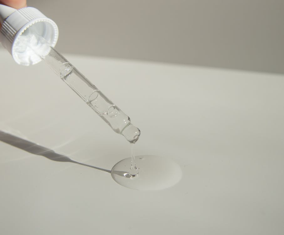 Free Anonymous person pouring liquid product on table with pipette Stock Photo