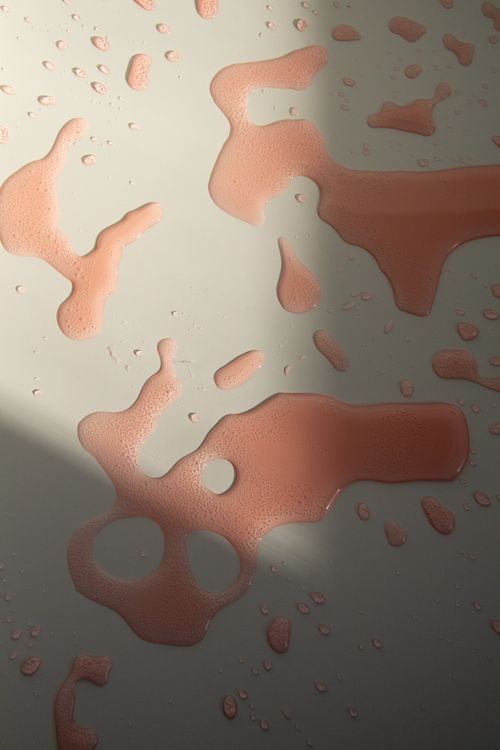 Free Top view of abstract drops of red colored fizzy water spilled on white table in sunlight Stock Photo
