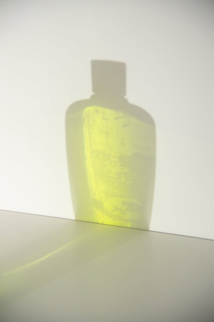 Shadow Of Bottle With Liquid Soap On White Wall