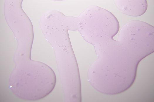 Abstract pattern of purple liquid on a smooth white background, offering vibrant texture and dynamic flow.