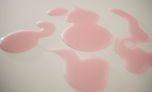 Free From above of textured background representing spilled pale pink liquid drips on smooth surface Stock Photo