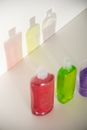 From above of assorted plastic bottles with colorful gels in row reflecting on white wall