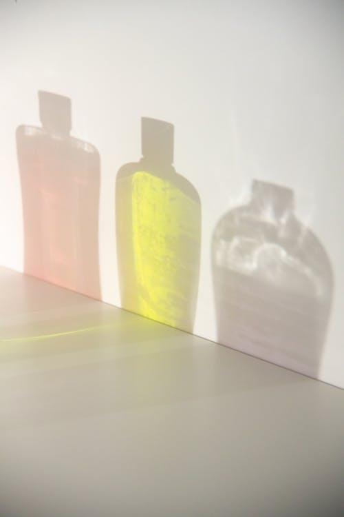 Assorted bottles of shampoos reflecting on wall