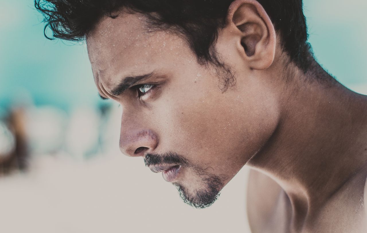 a close up portrait of a young man looking thoughtfully into the dista