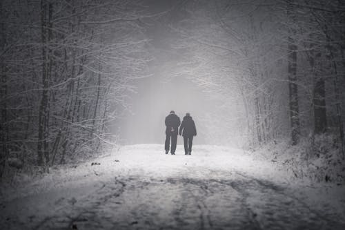 Persons Walking on Snow Covered Road