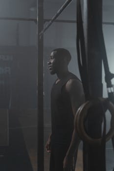 Side view of an African American man in a gym near pull-up bars, highlighting fitness.
