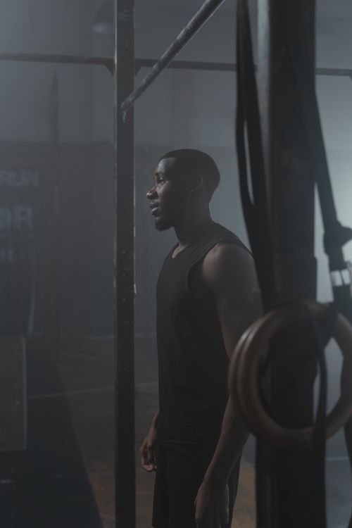 Free Side view of an African American man in a gym near pull-up bars, highlighting fitness. Stock Photo