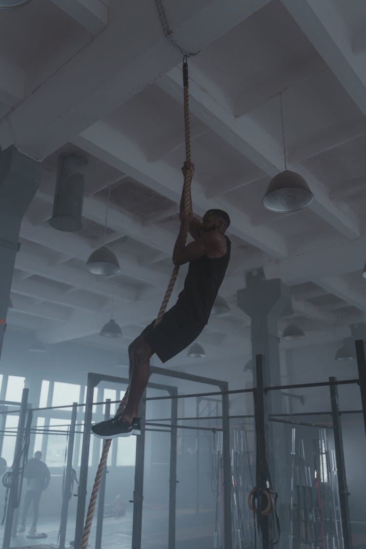 A Man In Black Tank Top Exercising In The Gym