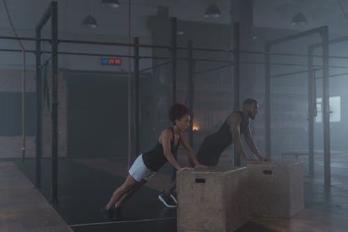 A Man and Woman in Black Tank Top Working Out Inside the Gym