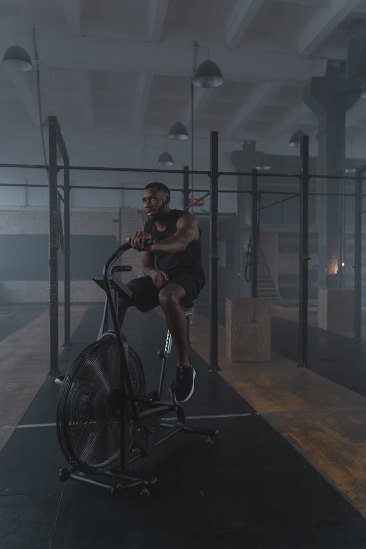 A Man In Black Tank Top Exercising In The Gym