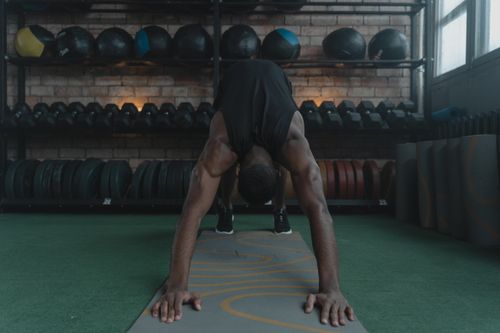 Free A man performing yoga, doing a downward facing dog pose in a gym environment. Stock Photo