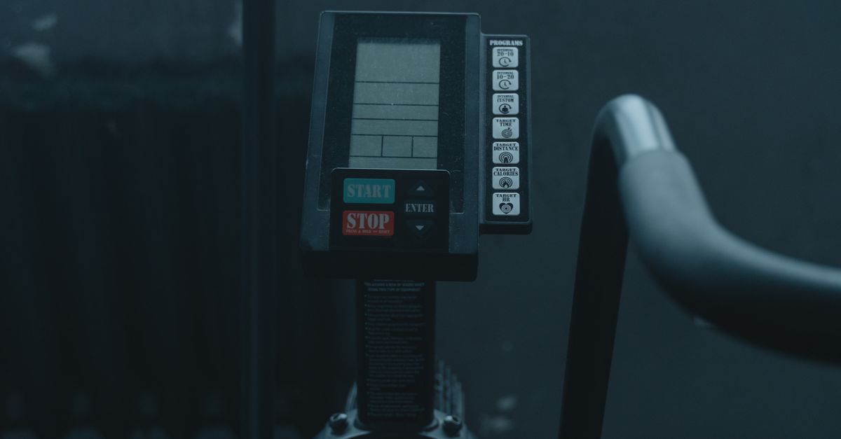 Close-up view of gym equipment with electronic monitor in a dimly lit indoor room, showcasing fitness technology.