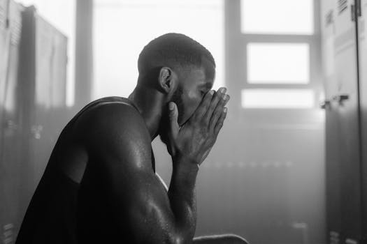 Black and white photo of a man sitting in a locker room, deep in thought.