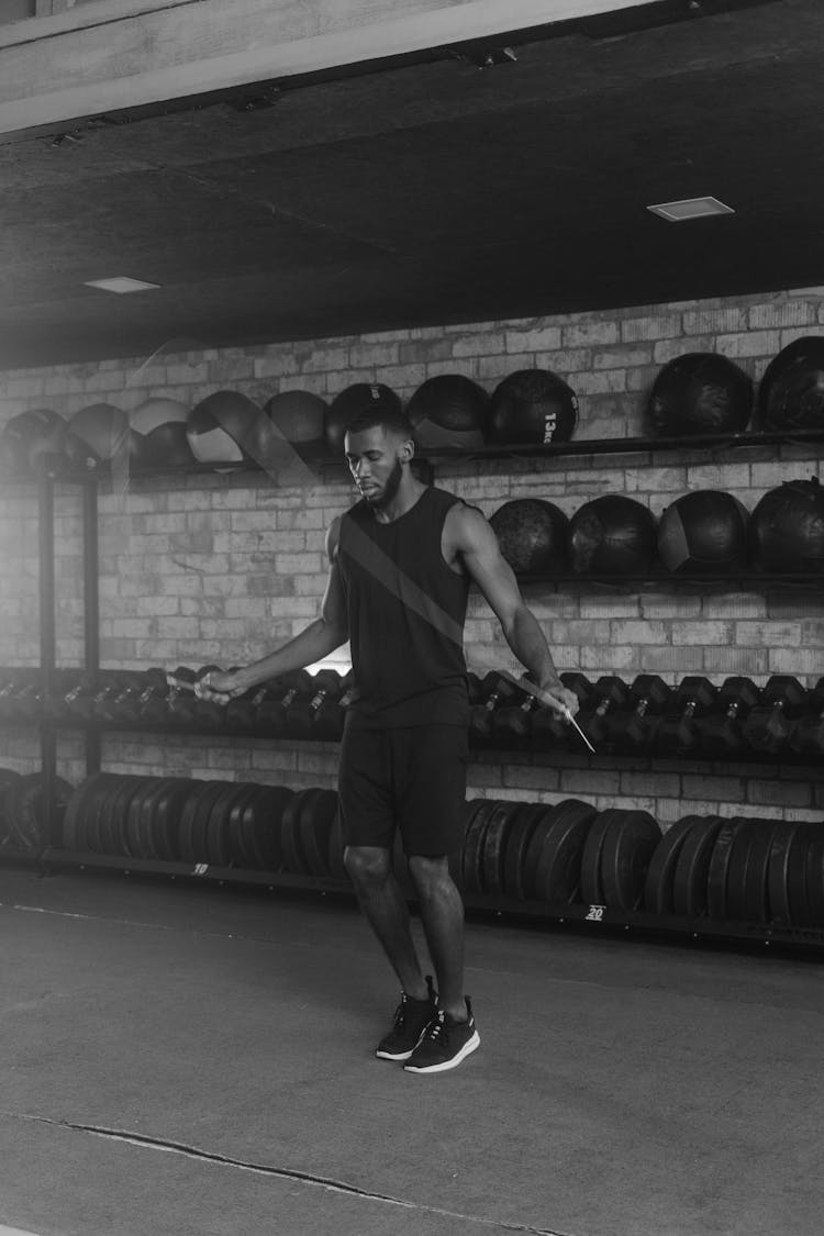 Grayscale Photo Of A Man In Black Tank Top Exercising In The Gym