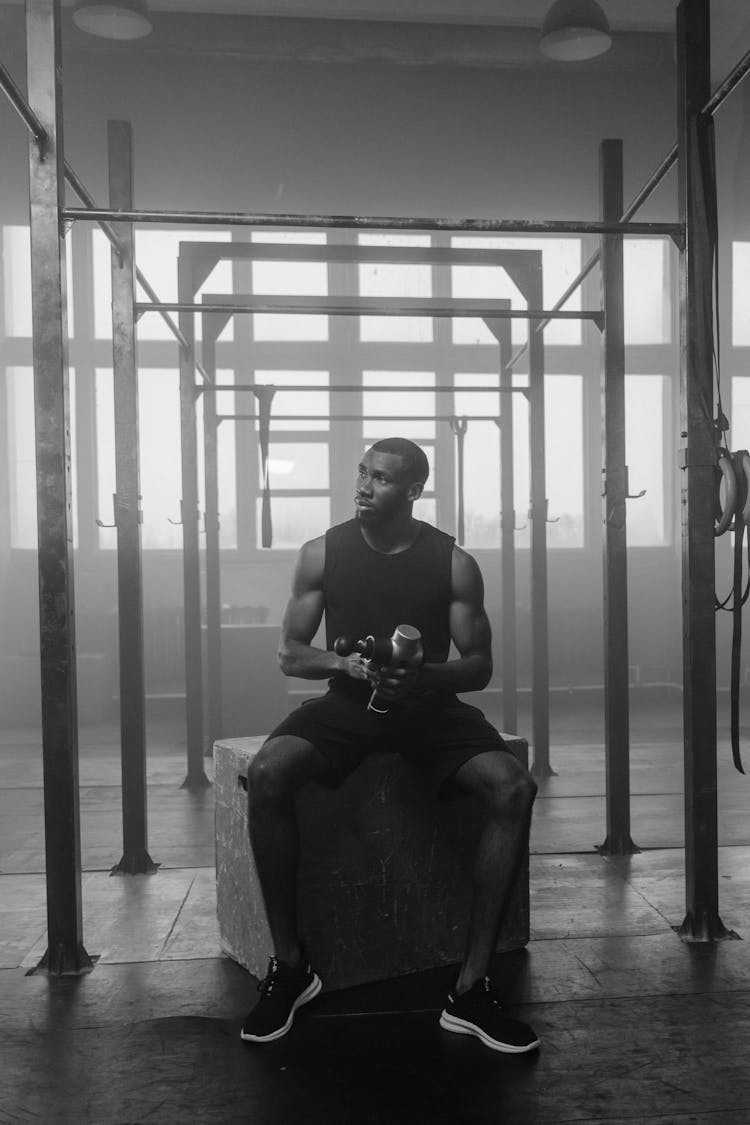 Grayscale Photo Of A Man In Black Tank Top Exercising In The Gym