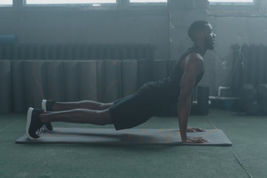 A man performing a yoga pose on a mat in a gym setting, embracing healthy living.
