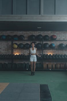 Woman in a gym performing jump rope exercises focused on fitness and wellness.