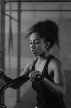 Focused African American woman working out in a gym, grayscale photo.