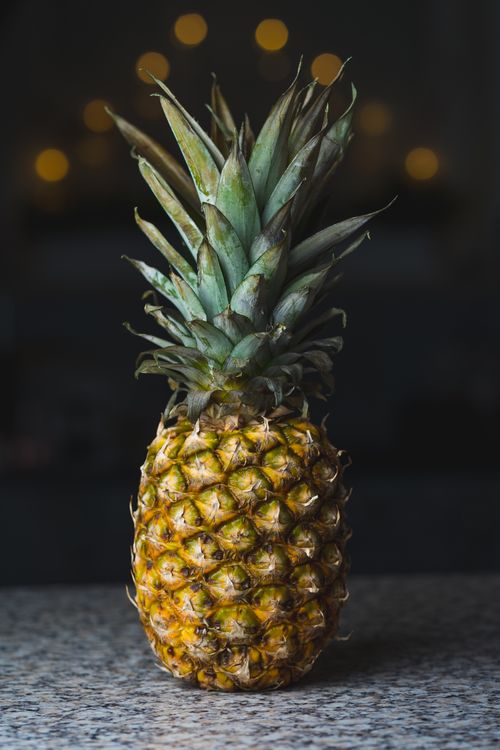Free Close-up of a pineapple with blurred lights in the background, perfect for food and lifestyle themes. Stock Photo