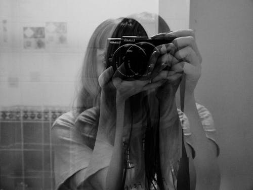 A Grayscale Photo of a Woman Holding a Black Camera