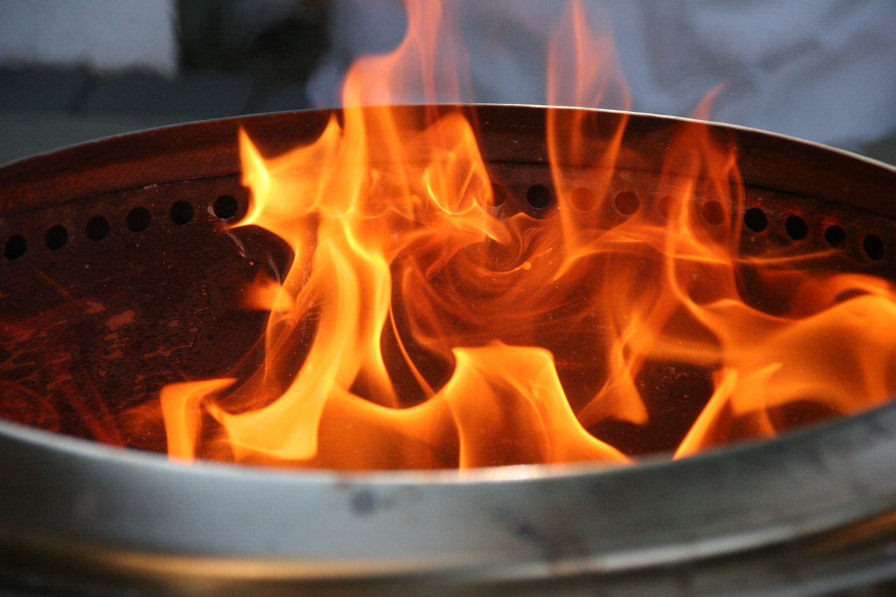 close up image of bright orange flames dancing inside a metal fire pit