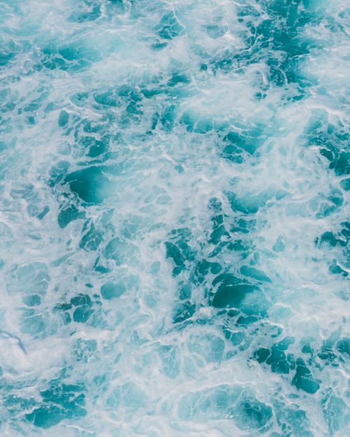 Free Aerial view of turquoise ocean waves creating vibrant sea foam patterns. Stock Photo