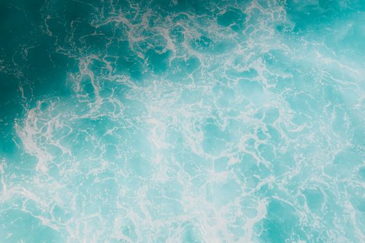 Captivating aerial shot of turquoise ocean waves with frothy seafoam, showcasing natural beauty.