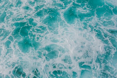 Free A stunning aerial shot capturing turquoise ocean waves with white sea foam. Stock Photo