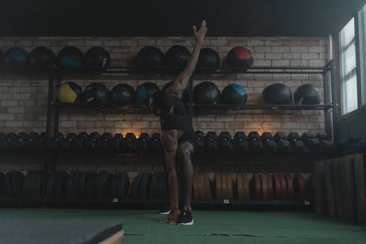 African American man stretching in a gym with equipment in the background.