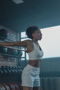 African American woman stretching indoors in a gym, highlighting fitness and wellness.