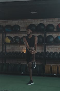 Fit African American man stretching in an indoor gym, surrounded by exercise equipment.