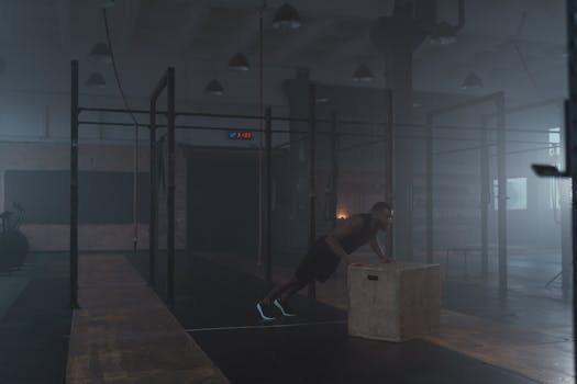 African American man focused on a box push-up workout inside a dimly lit gym.