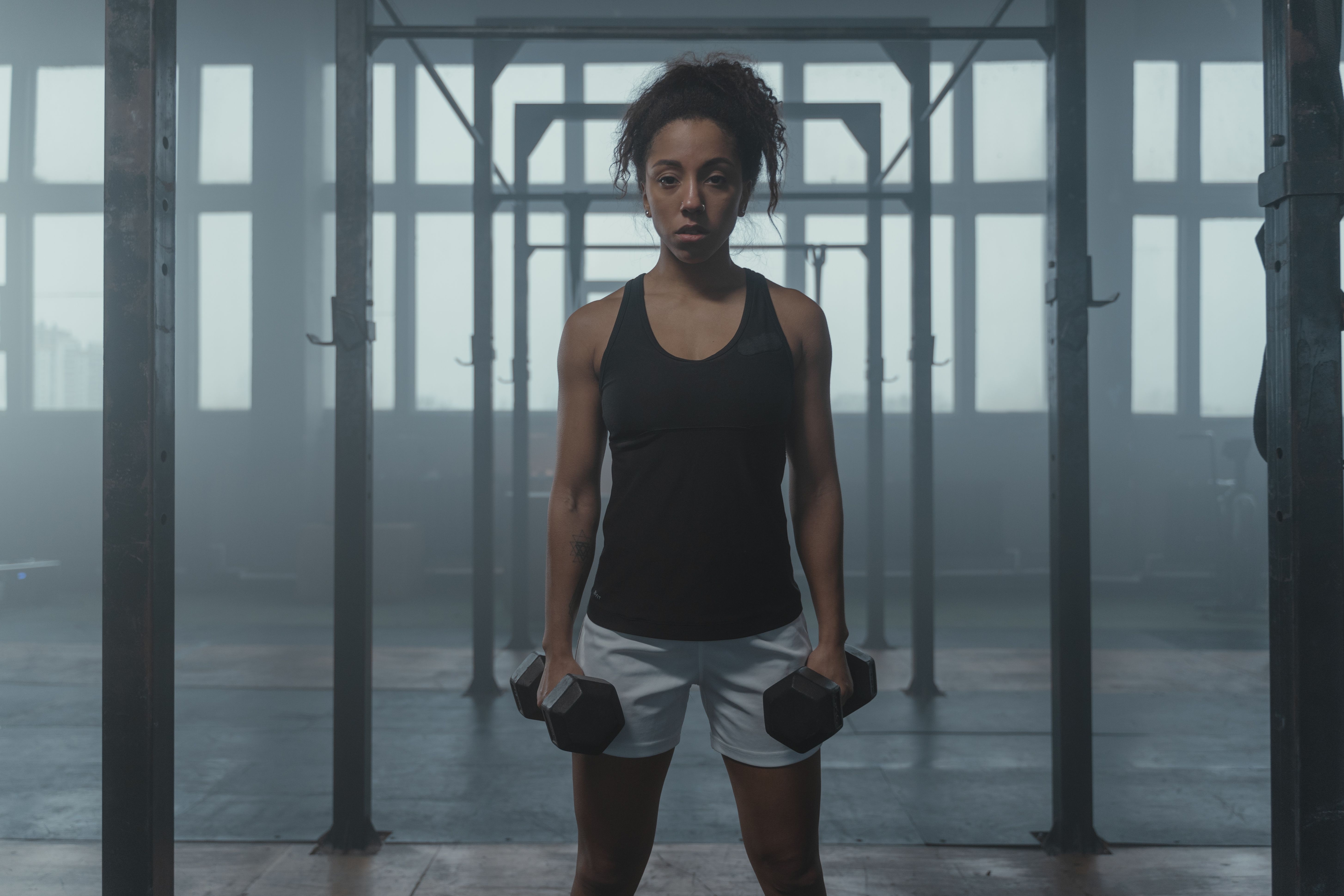 Determined woman lifting weights, showcasing fitness and strength in a gym setting.