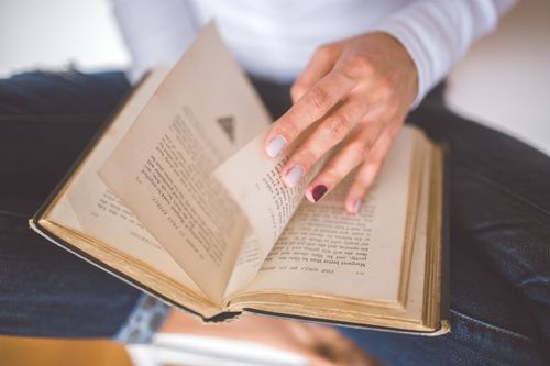 Free A woman flips through the pages of an old book, focused on reading and learning. Stock Photo