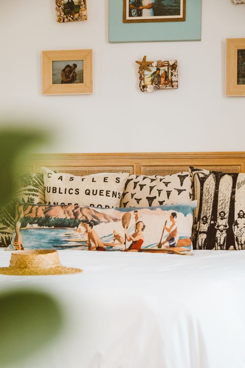 Free A bed with artistic pillows and framed pictures on the wall creating a cozy and stylish ambiance. Stock Photo