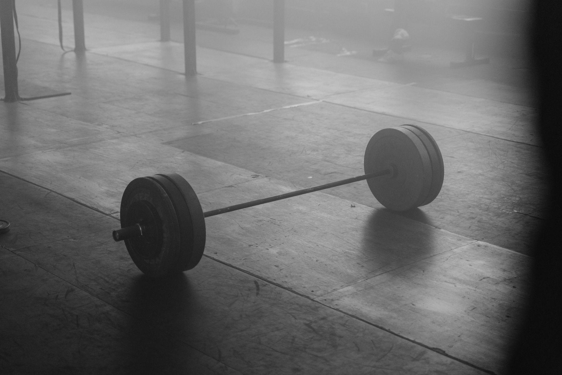 A loaded barbell resting on the floor of an empty weight room