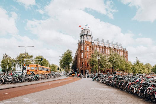 Urban scene with crowded bicycle racks near a historic building in Amsterdam on a sunny day.