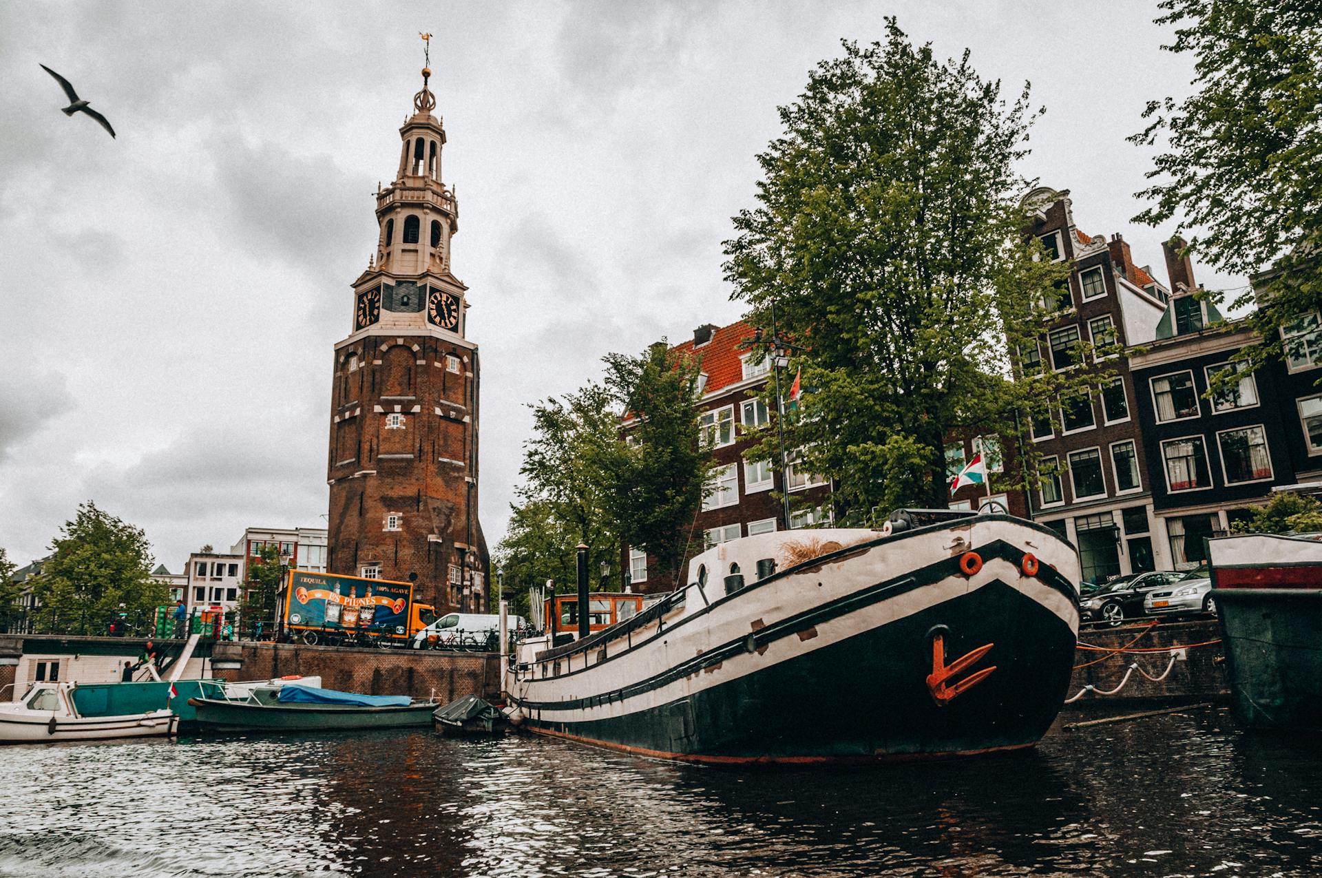 Boats Docked on a Canal with the Zuiderkerk Tower at the Background