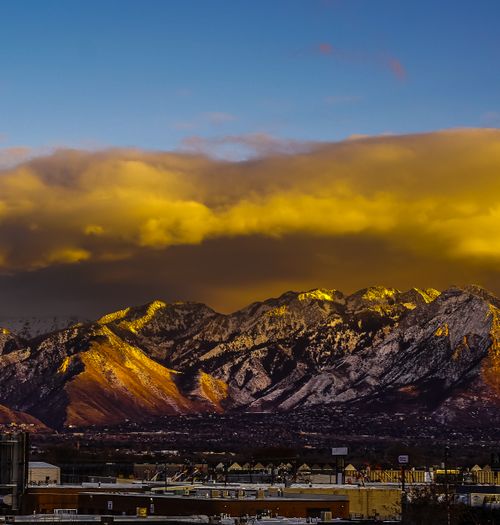 Free Stunning view of snow-capped mountains with golden clouds over Salt Lake City at sunset. Stock Photo