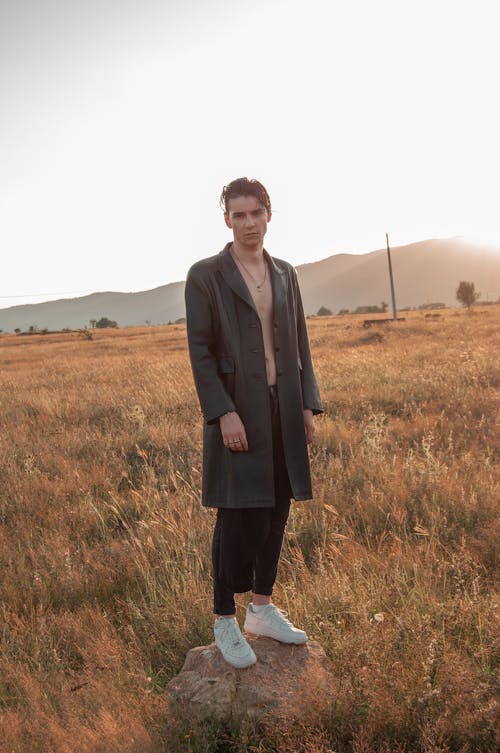 Stylish man standing on stone in grassy lawn