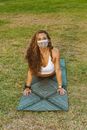 Woman in White Tank Top and Blue Denim Shorts Sitting on Blue and White Striped Mat