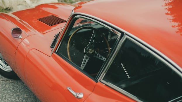 A high-angle view of a gleaming red vintage sports car showcasing its elegant wooden steering wheel.