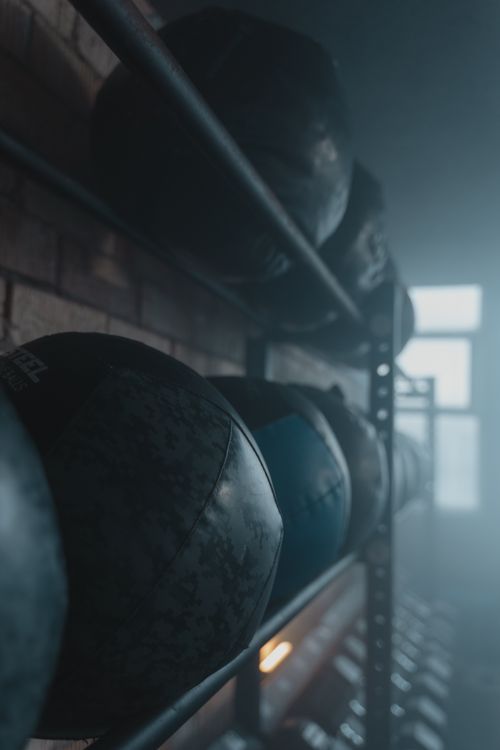 Free Rows of medicine balls in a dimly lit gym interior, emphasizing fitness and strength. Stock Photo
