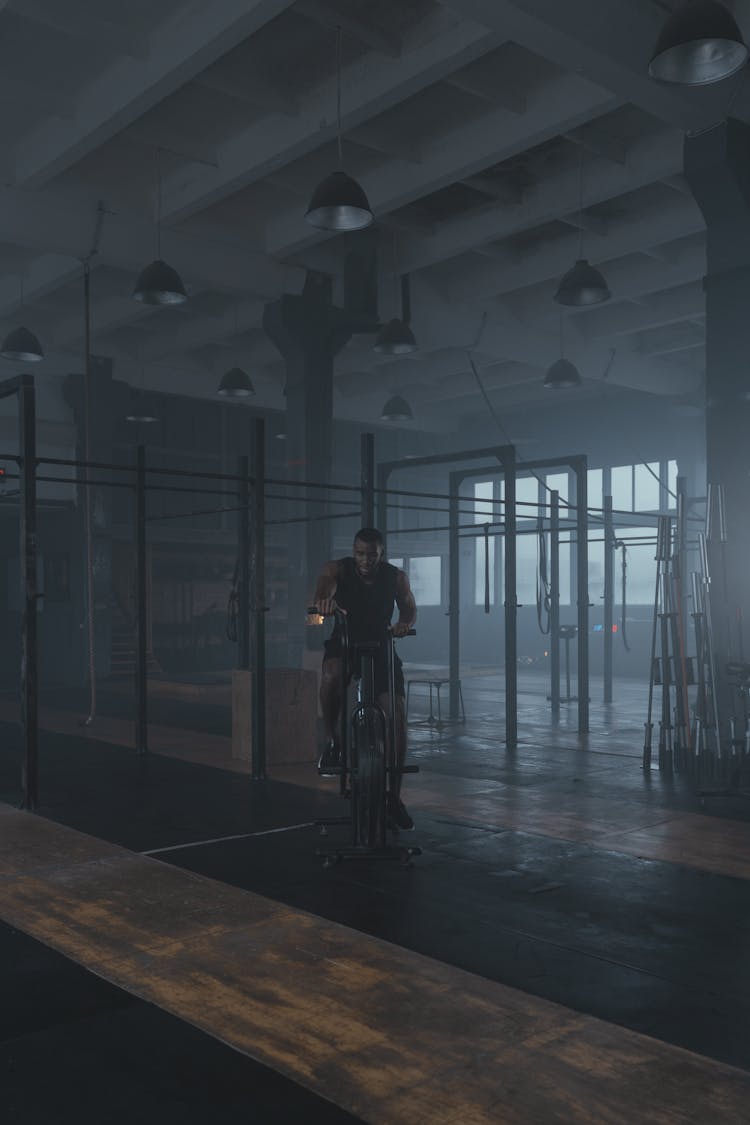 A Man In Black Tank Top Using An Air Bike At The Gym