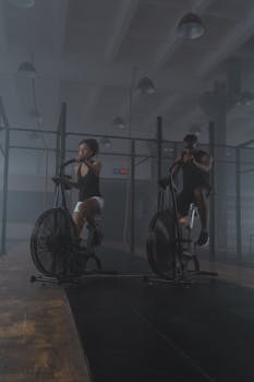 A focused pair of athletes exercising on air bikes, showcasing endurance and fitness in a gym setting.