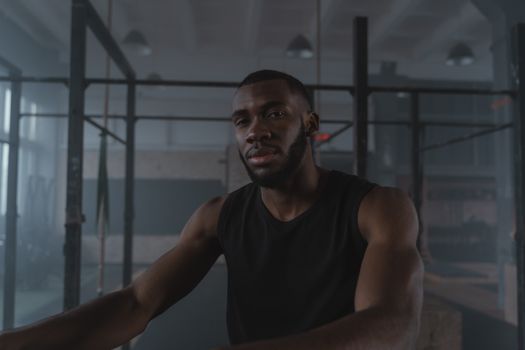 Portrait of a bearded man in a black tank top at the gym, expressing confidence.