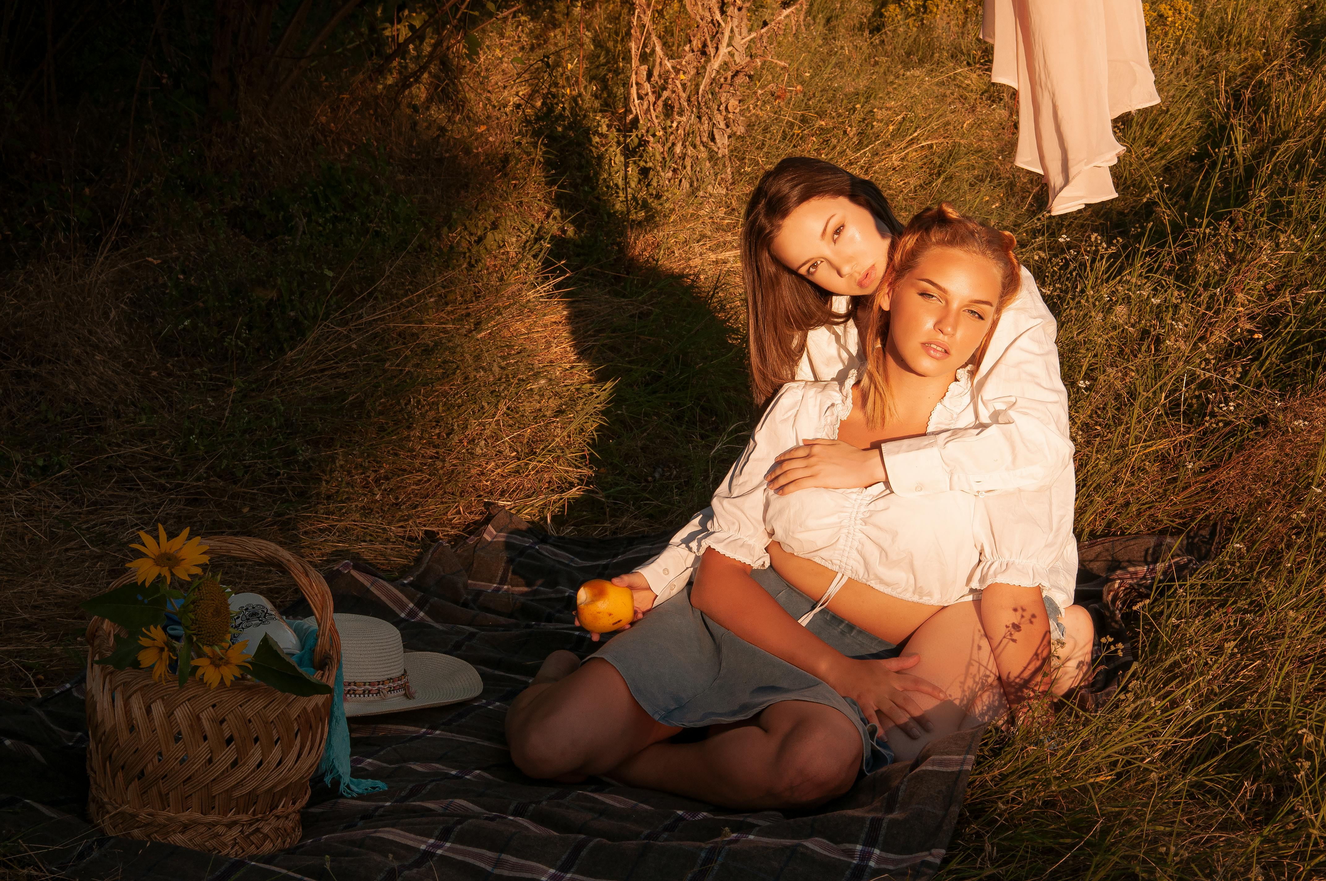 gentle women sitting on blanket in meadow