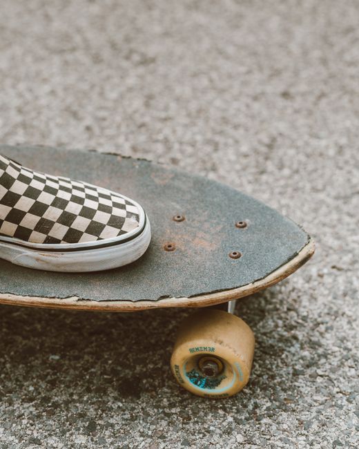 Close-up of a checkered shoe on a skateboard outdoors on a street.